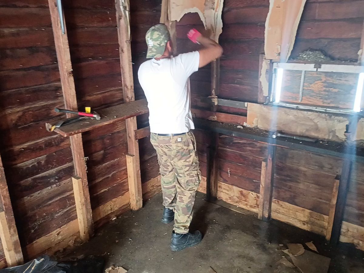 Ty James of Pioneer Valley Junk Removal tearing out old paneling inside a garage on Gillette Avenue in Springfield, MA