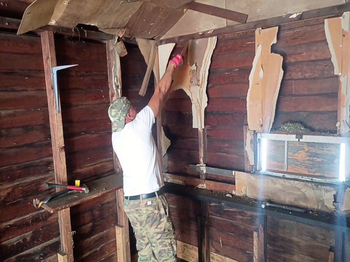 Ty James pulling damaged paneling off the wall during a garage cleanout in Springfield