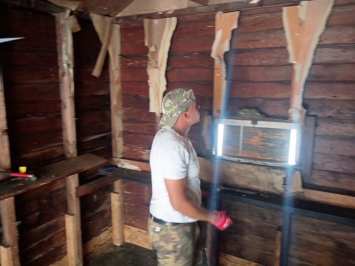 Ty James reaching up to clear old paneling from a garage wall in Springfield, MA